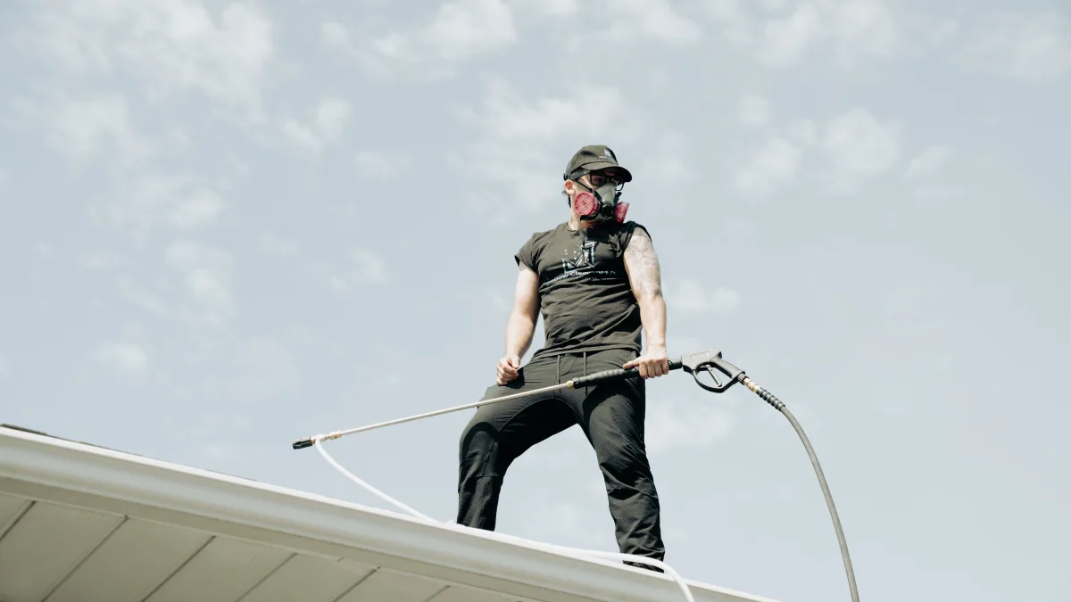 Technician pressure washing from a rooftop